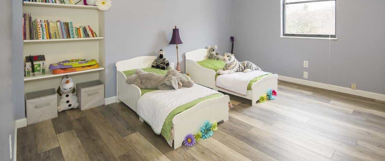 A neat kids' bedroom featuring two single beds and a shelf.